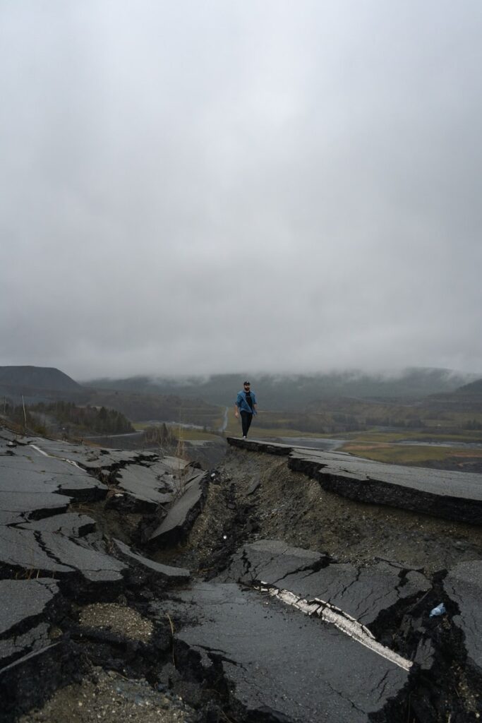 man in blue jacket standing on rock formation during daytime