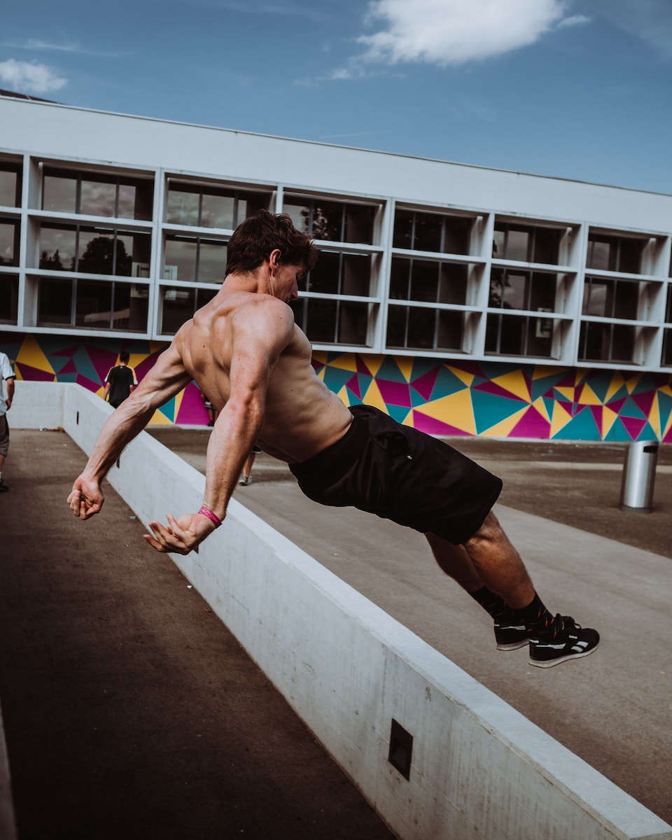 man in black shorts and black nike shoes doing push up