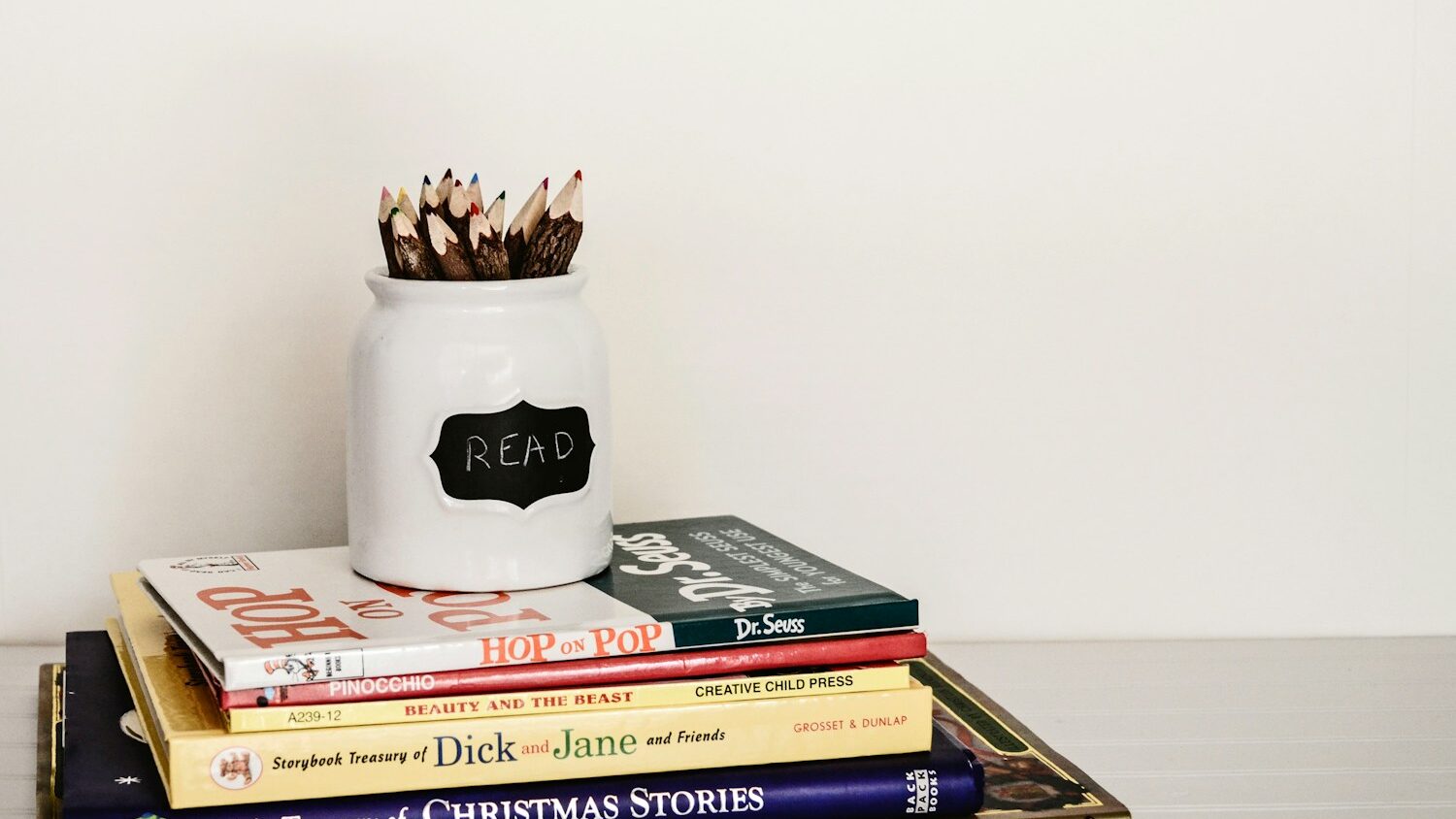 white ceramic pencil organizer on top of stack of books