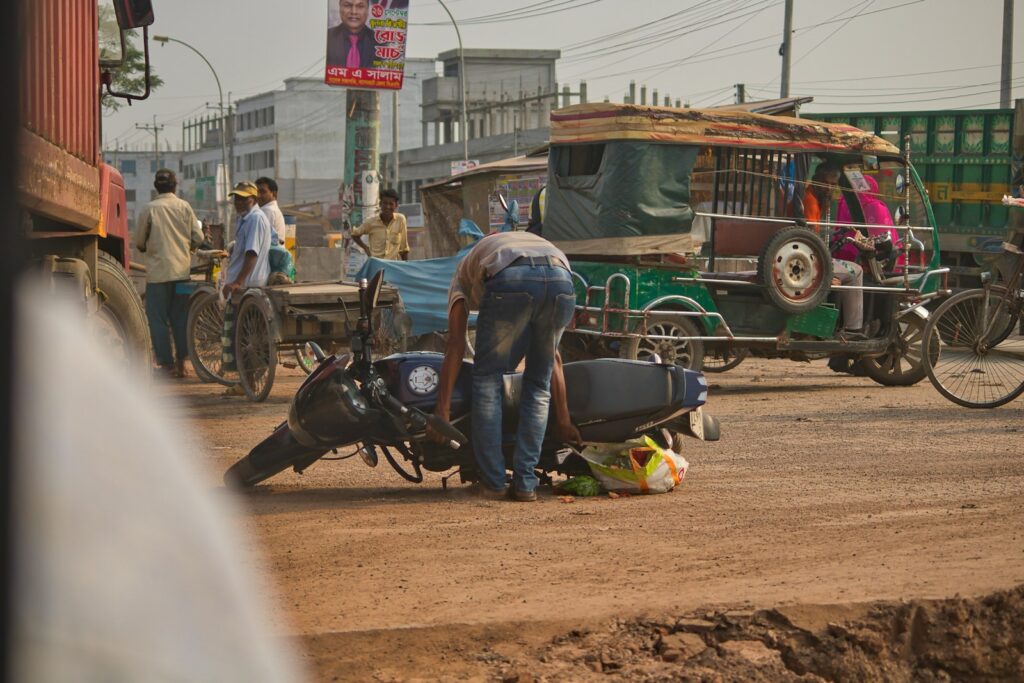 a group of people standing around a motorcycle on a dirt road