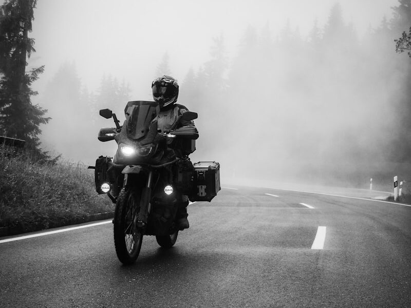 a man riding a motorcycle down a foggy road