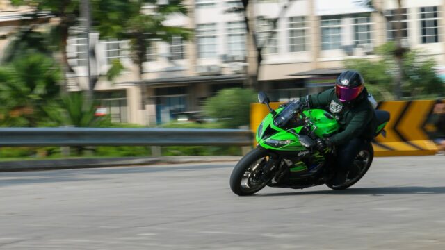 a man riding a green motorcycle down a street