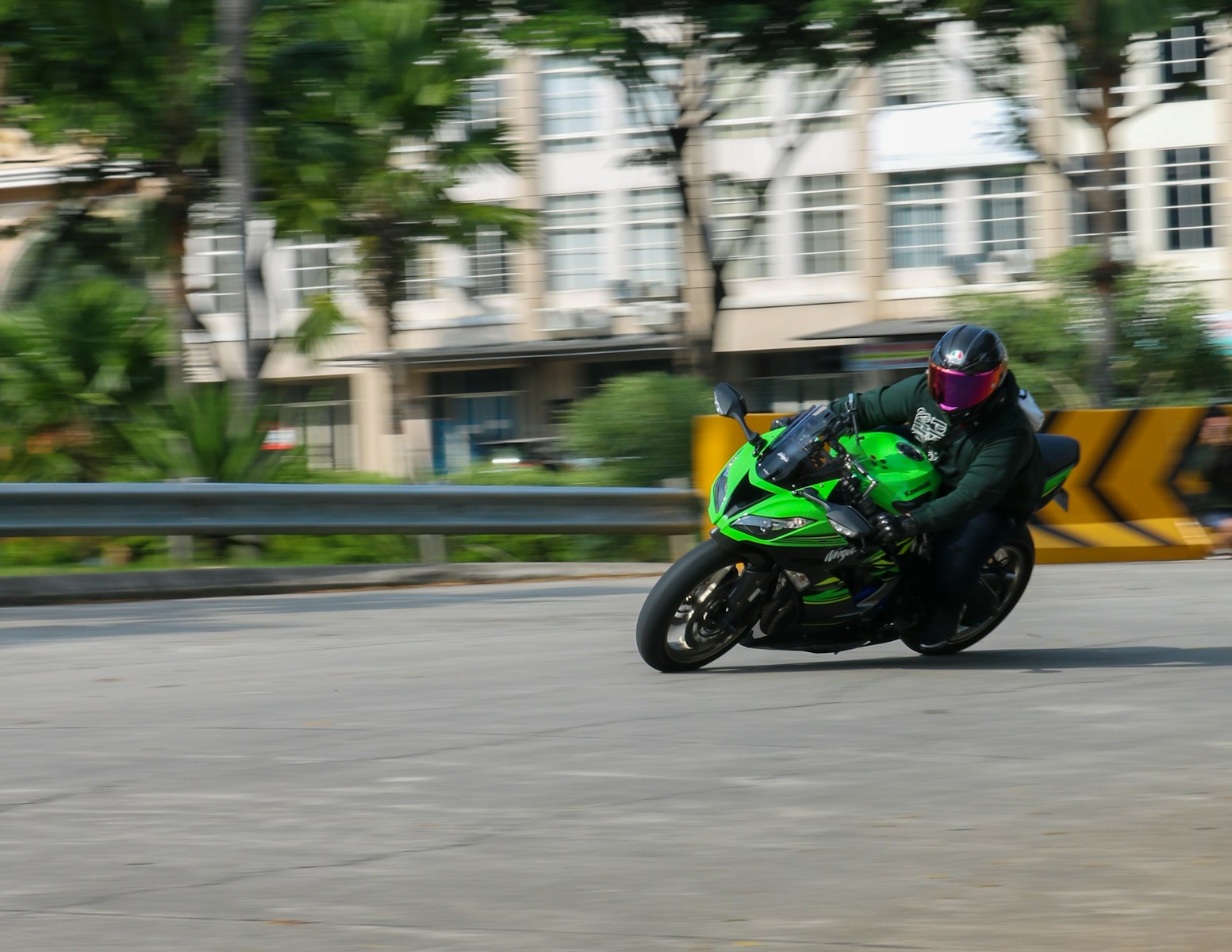 a man riding a green motorcycle down a street
