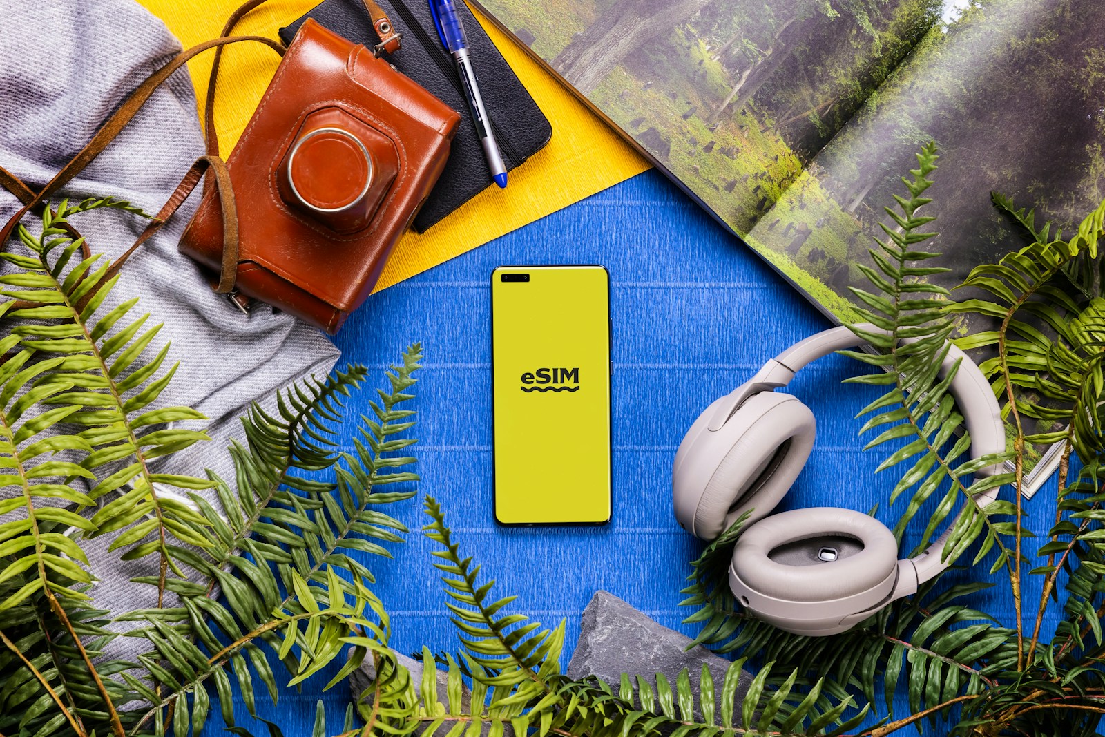 A book, headphones, a camera, and a cell phone on a table