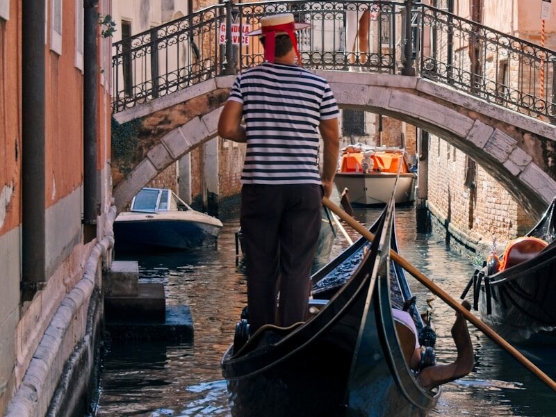 a man riding a gondola down a narrow street